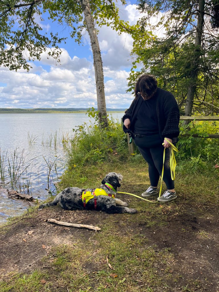 Photo of a woman and a dog near a lake.